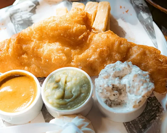 Close up of plate of fish and chips with sauces