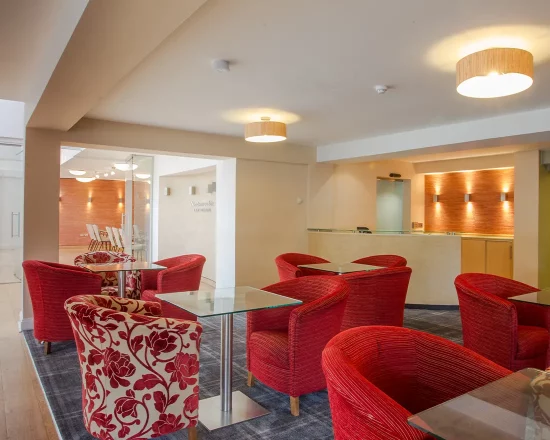 Lounge area with red tub chairs and tables