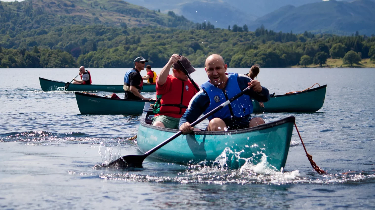 People having fun on a team building exercise canoeing on Lake Windermere in Canadian canoes