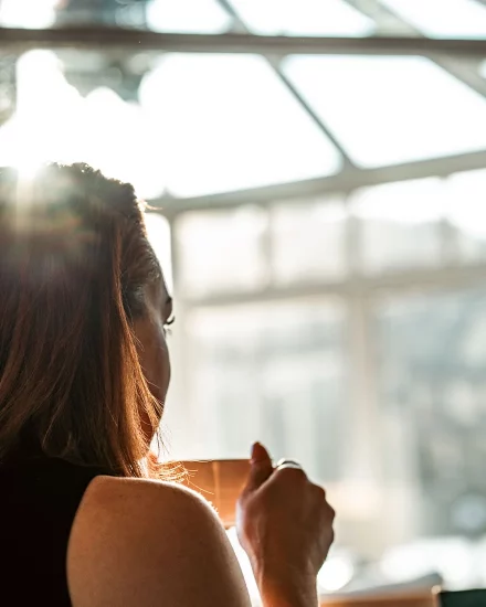 Image link of a content woman in thought drinking a cup of coffee in the conservatory at Lakeside Hotel