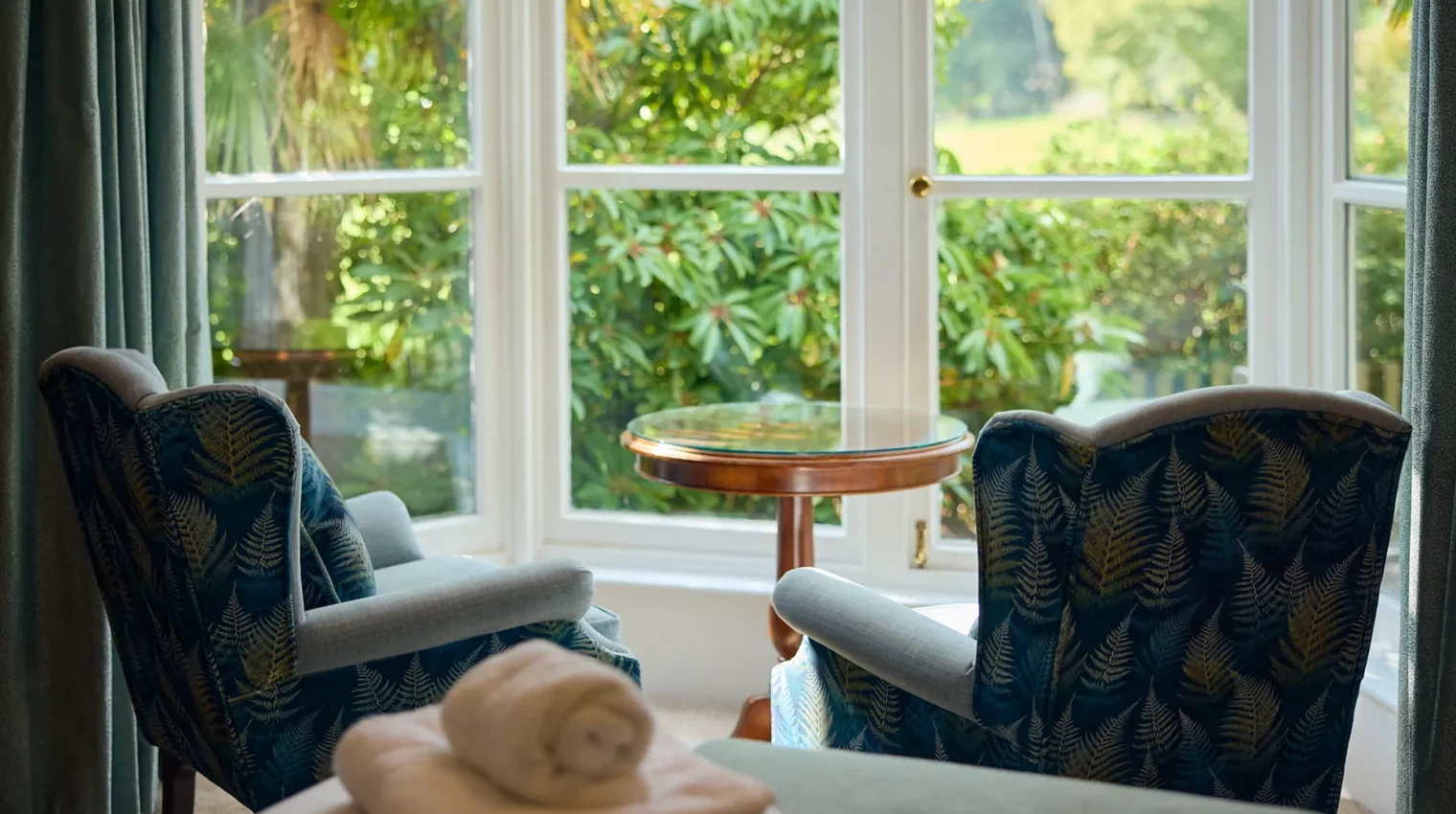 Two modern comfortable chairs next to the window looking out onto a garden