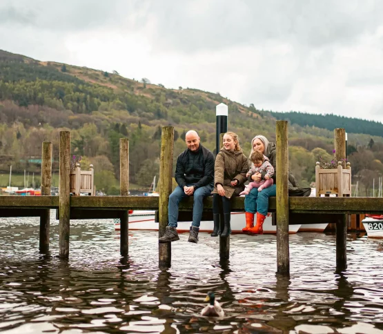 A family sat together dangling their feet off a lake jetty