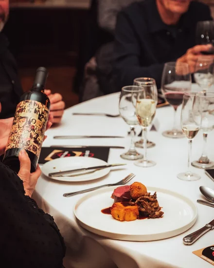 Person reading a wine label at the table