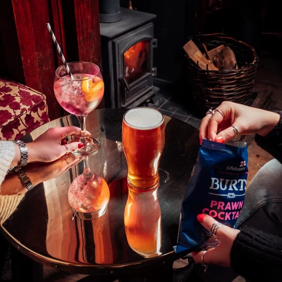 A table with a pint of beer and a gin and tonic in a traditional pub setting