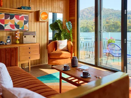 Bright wood panelled room with retro decor and a lake view