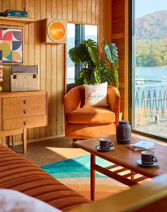 Bright wood panelled room with retro decor and a lake view