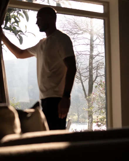 A man opens the curtains in his hotel room to reveal the lake view