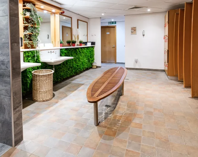 Modern spa and pool changing rooms with tiled floor and wooden bench