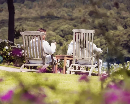 Two girls in gowns on loungers in the spa garden overlooking the lake