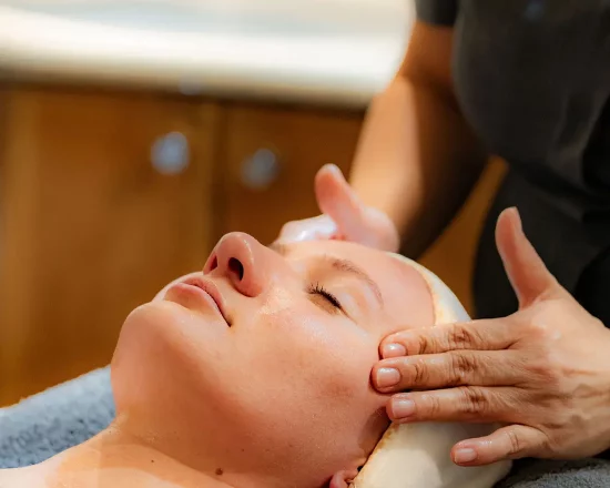 Woman having a facial with spa therapist hands massaging face