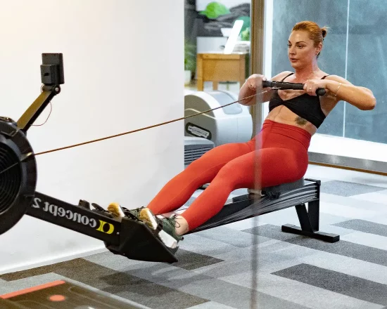Active woman on rowing machine in modern hotel gym