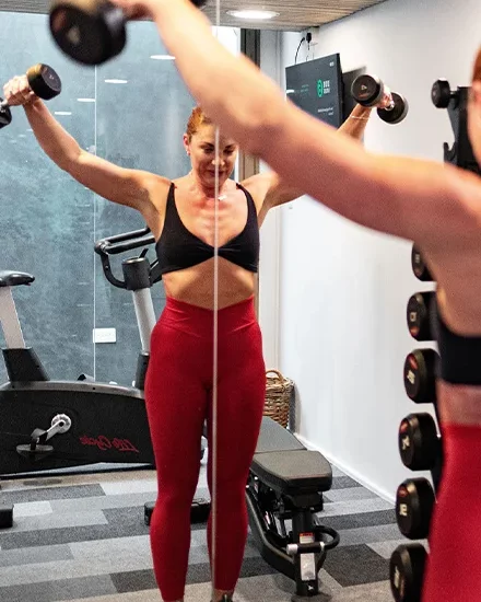Woman working out with weights in gym clothing