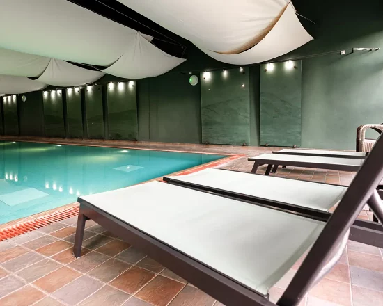 Inside swimming pool with cream loungers on the side