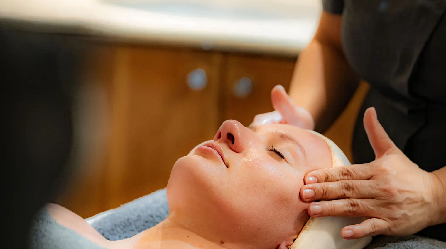 Woman having a facial with spa therapist hands massaging face