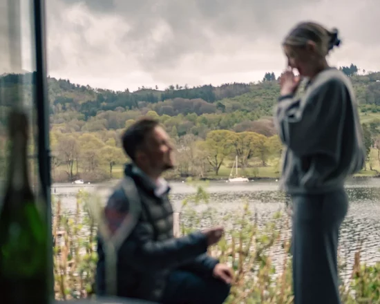A man is down on one knee proposing to his partner in front of the potting shed