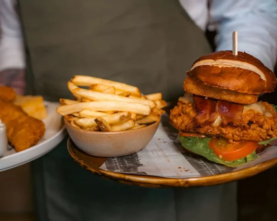 A plate of burger and chips is carried by a waiter