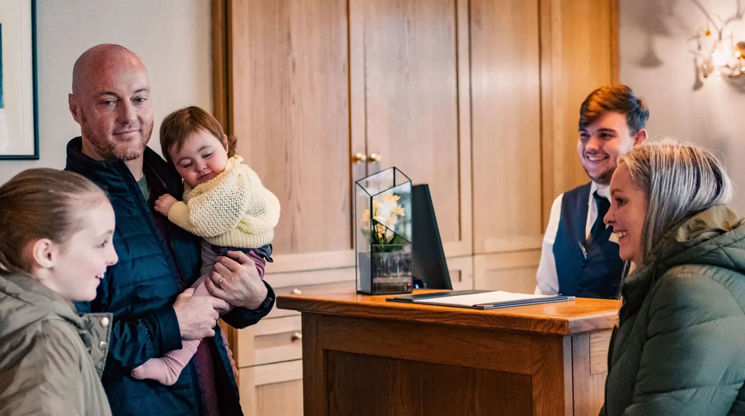 Member of the Lakeside Hotel Front Desk team greets a family at the hotel reception