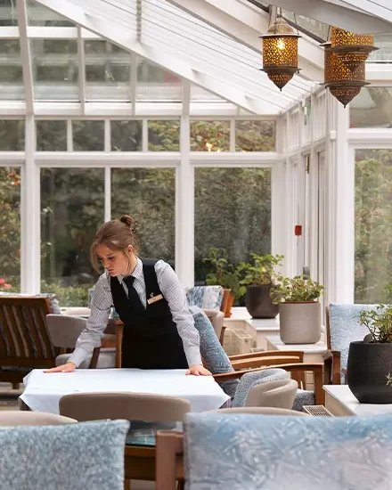 Member of the Lakeside team setting tables in the conservatory