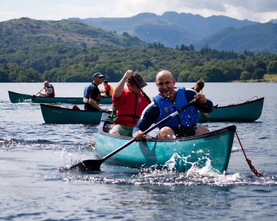 People having fun on a team building exercise canoeing on Lake Windermere in Canadian canoes
