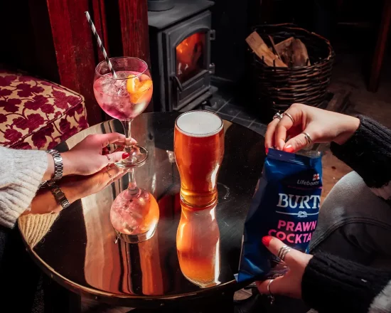 A table with a pint of beer and a gin and tonic in a traditional pub setting