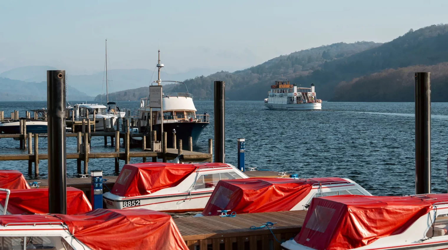 Small hire boats tied up to the jetty on the shore at Lakeside Hotel