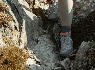 Close up of a person clambering down a rocky path, wearing hiking boots