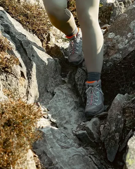 Close up of a person clambering down a rocky path, wearing hiking boots