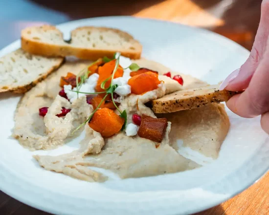 A vegetarian dish made with humous and tomatoes, being eaten with bread