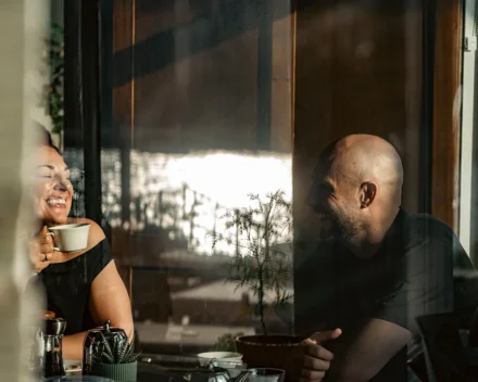 Couple laughing together through window at breakfast