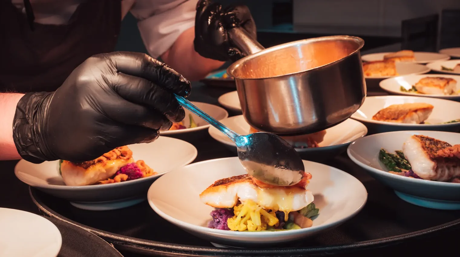 Chef delicately pouring sauce on a dish in the Lakeview Restaurant kitchen