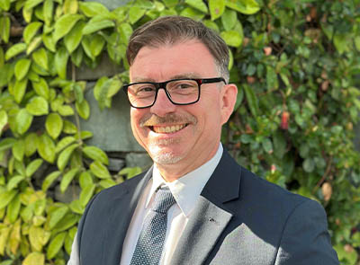 Head and shoulders of Lakeside Hotel team member with leafy background