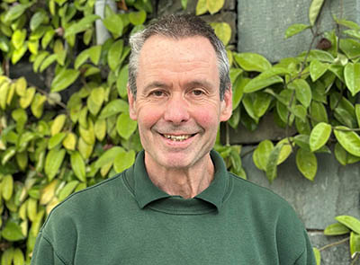 Head and shoulders of Lakeside Hotel team member with leafy background