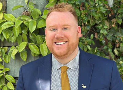 Head and shoulders of Lakeside Hotel team member with leafy background
