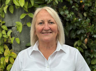 Head and shoulders of Lakeside Hotel team member with leafy background