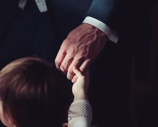 A small boy holds his Dad's hand at a wedding