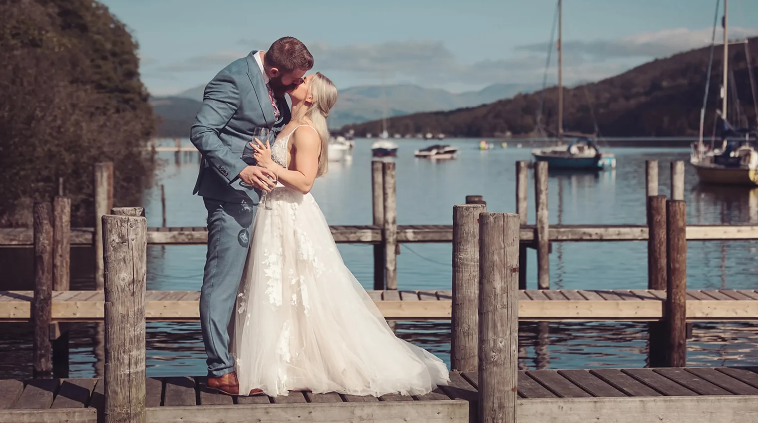 Married couple celebrating their wedding with a kiss on the jetty with the stunning backdrop of Lake Windermere