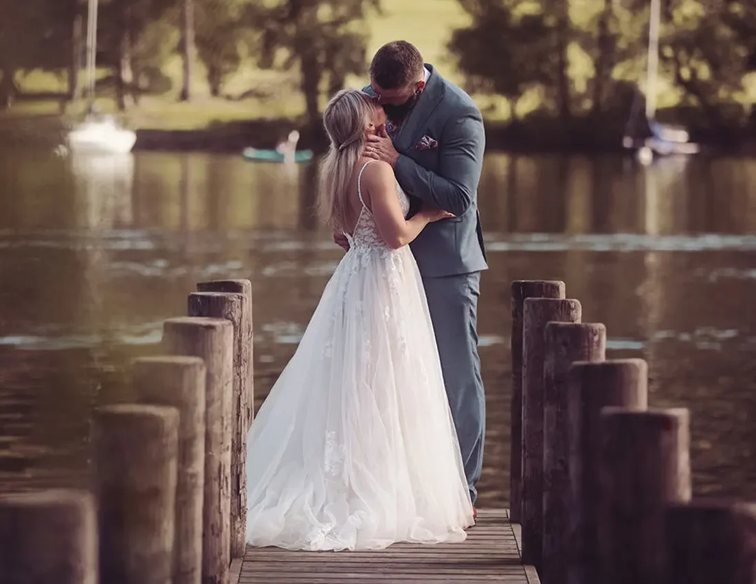Newlyweds enjoy the view and a kiss, at the end of the jetty overlooking Lake Windermere
