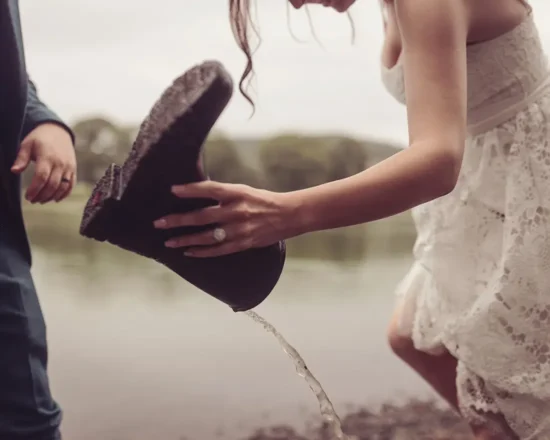 A bride on the shore of the lake, pours out water from a boot