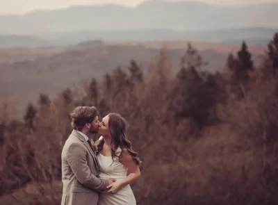 Newly married couple kiss in front of a backdrop of Lake District fells