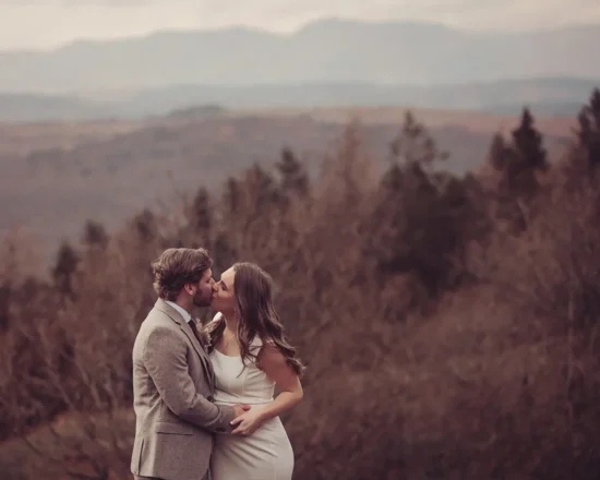 Newly married couple kiss in front of a backdrop of Lake District fells