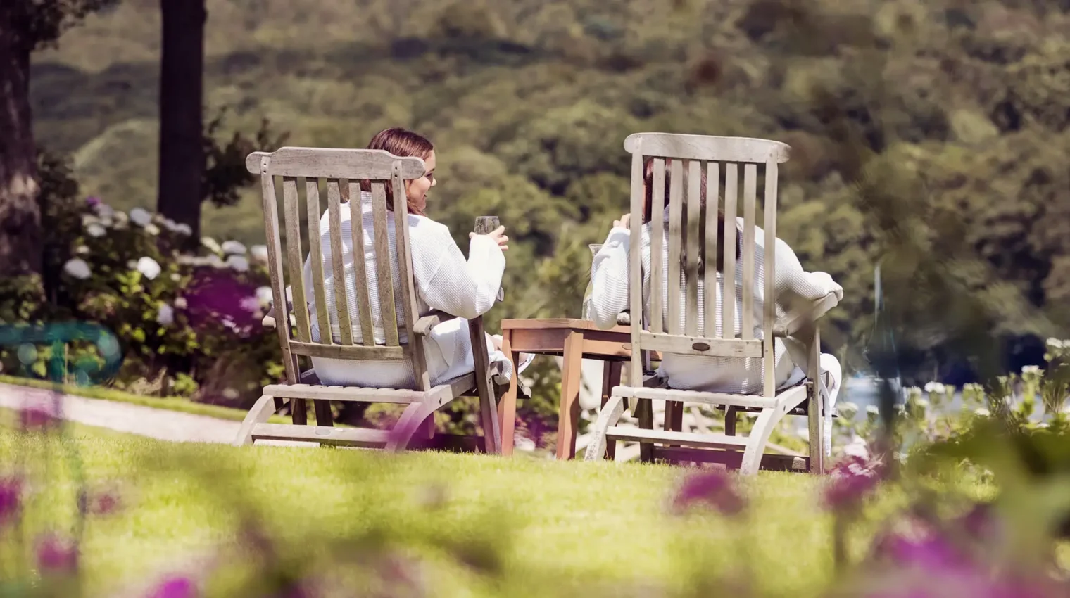 Two girls in gowns on loungers enjoying the view of Lske Windermere from the spa garden