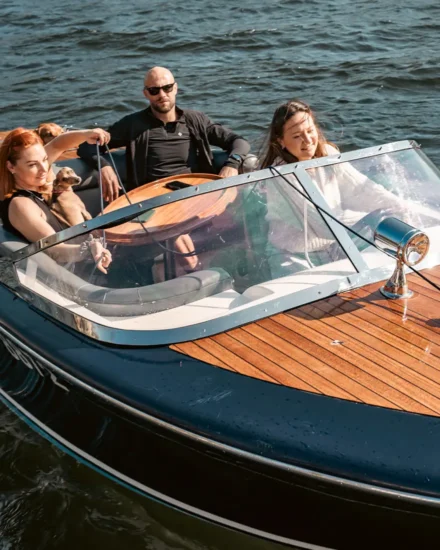 A group of friend enjoying a boat experience sailing along Lake Windermere in the sunshine