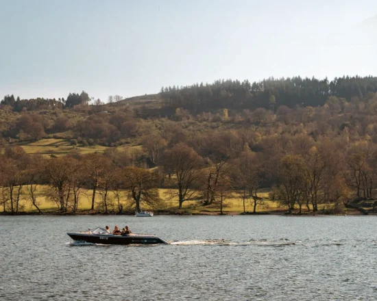 A landscape view across Lake Windermere with a hire boat cruising across the water