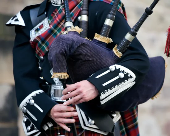 Close up of bag piper in traditional Scottish tartan dress
